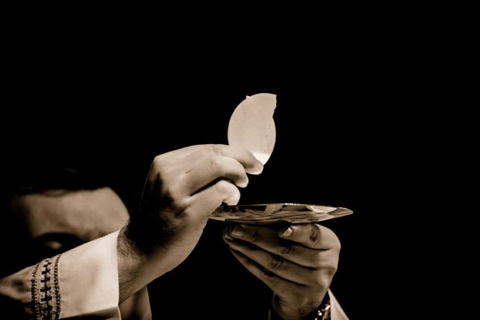 Eine Hand, die den Leib Christie bei der Eucharistie hält.