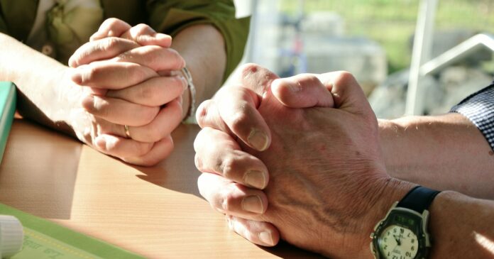 Zwei betende Personen mit verschränkten Fingern.