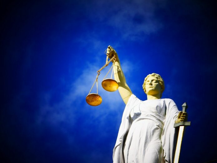 Justitia-Figur vor blauem Himmel.