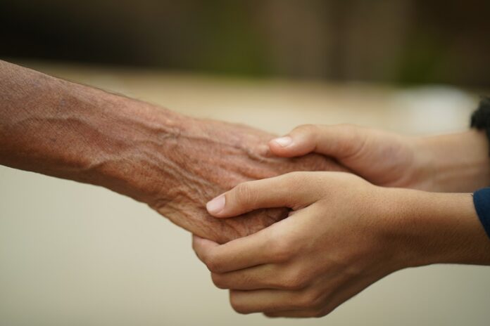 Hände einer jüngeren Person hält eine Hand einer älteren.