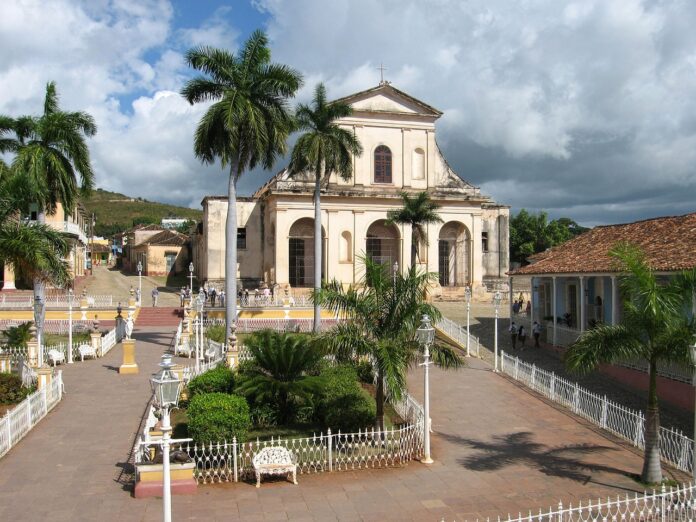 Kirche in Trinidad, Kuba. Im Vordergrund stehen Palmen.