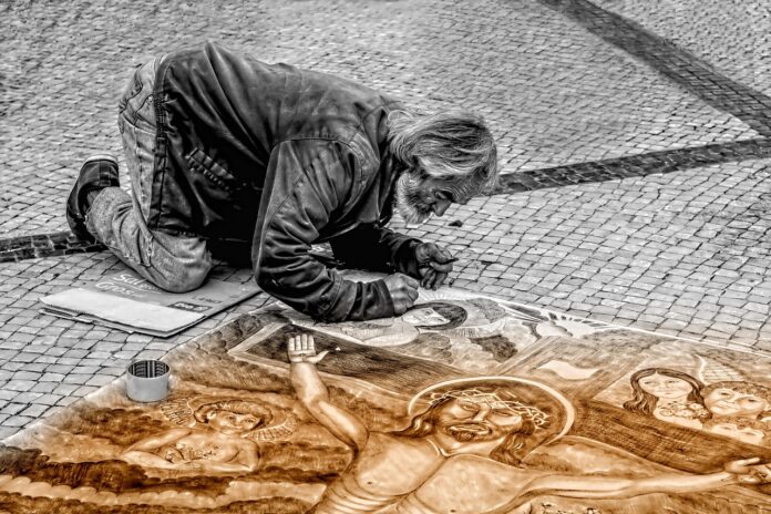 Straßenkünstler malt ein Bild von Jesus am Kreuz