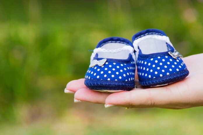 Blaue Babyschuhe auf einer Hand.
