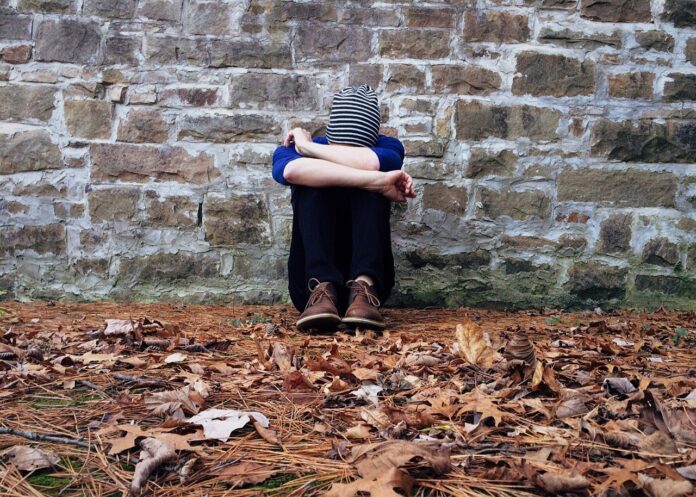Einsamkeit von Kinder - Mann sitzt einsam vor einer Mauer