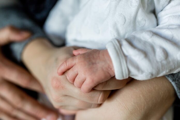Die Hände von einem Baby, der Mutter und dem Vater.