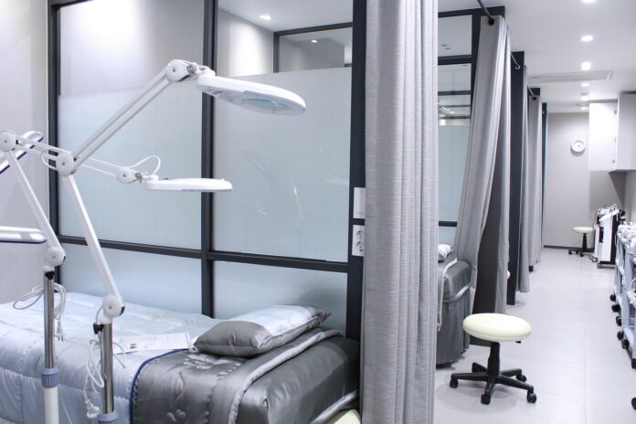 Blick in ein Krankenhaus. Verschiedene Behandlungszimmer, die mit Vorhängen und Milchgläsern abgetrennt sind.