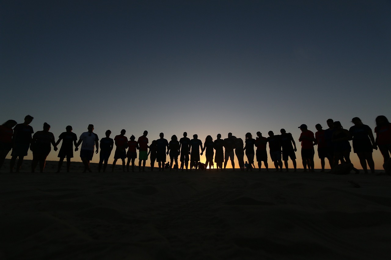 Menschen stehen Arm in Arm und schauen in den Sonnenuntergang
