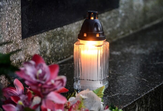Eine Kerze und Blumen auf einem Grab.
