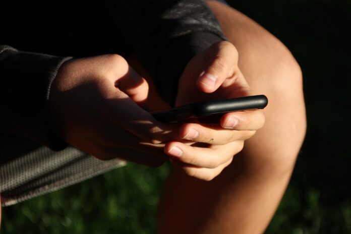 Ein Jugendlicher ist am Handy vertieft